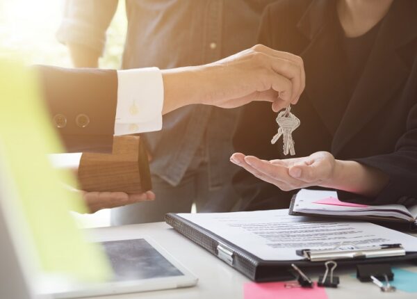 estate agent giving house keys to couple and sign agreement in office